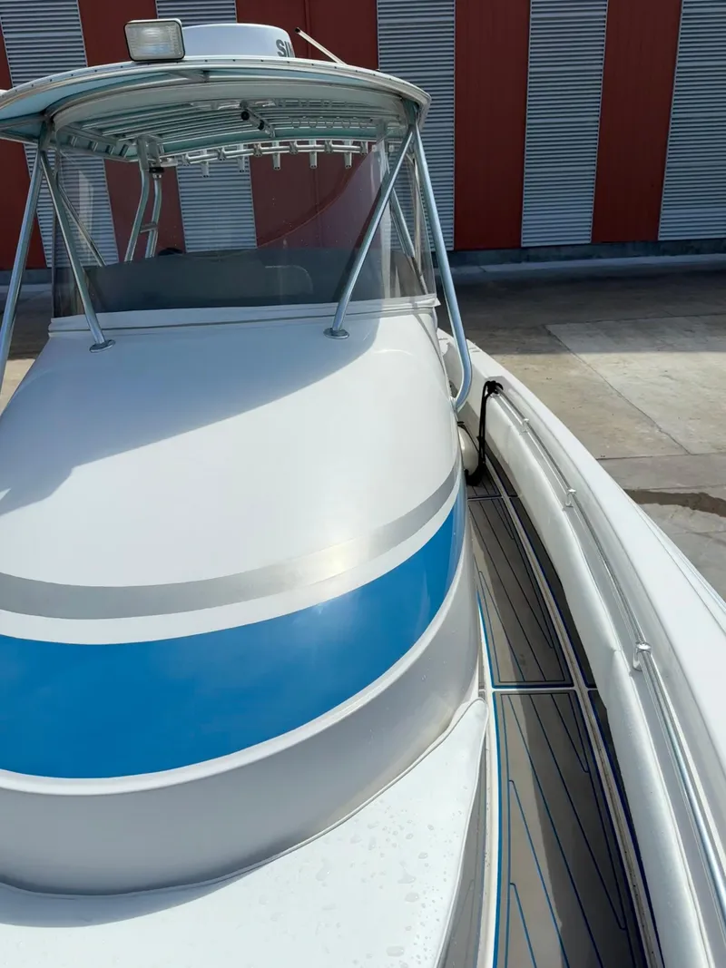 Slide: The Image of 2007 Contender 36 Fish Around boat with blue stripe, docked near red and white building. - 5