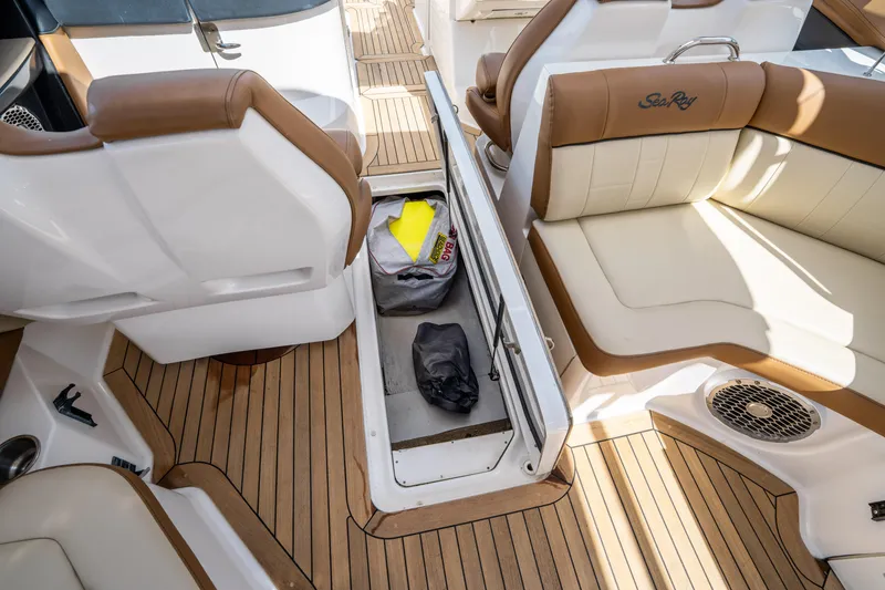 Slide: The Image of 2015 Sea Ray 350 SLX interior with open storage compartment, brown and white seating, and teak flooring. - 38