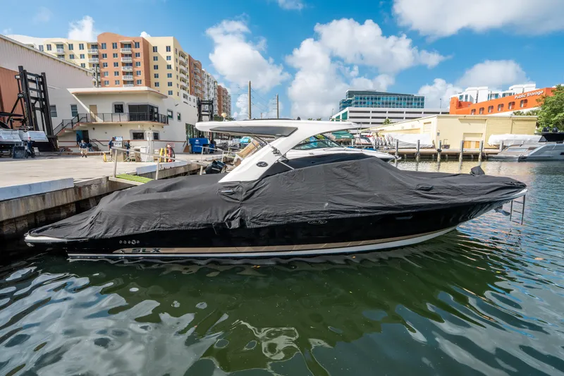 Slide: The Image of 2015 Sea Ray 350 SLX boat docked with cover, urban marina backdrop. - 7