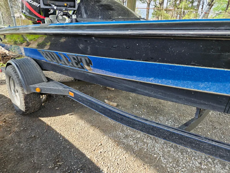Slide: The Image of 1993 Bullet 20XD boat on trailer, black and blue design, parked outdoors. - 10