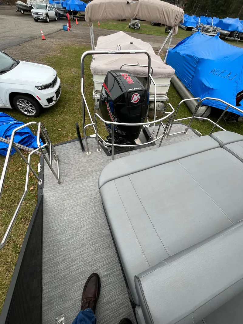 Slide: The Image of 2022 Bennington LXS SPORT 24 LXSB pontoon boat with Mercury outboard motor, parked outdoors. - 8