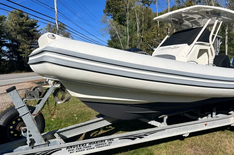 Slide: The Image of 2022 Brig Eagle 8 boat on trailer, parked outdoors, with trees and road in background. - 29