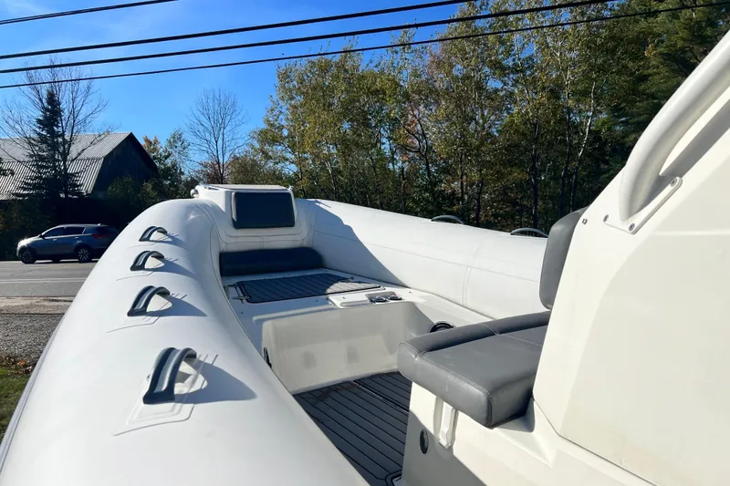 Slide: The Image of 2022 Brig Eagle 8 inflatable boat interior with seating, parked near a road and trees. - 32