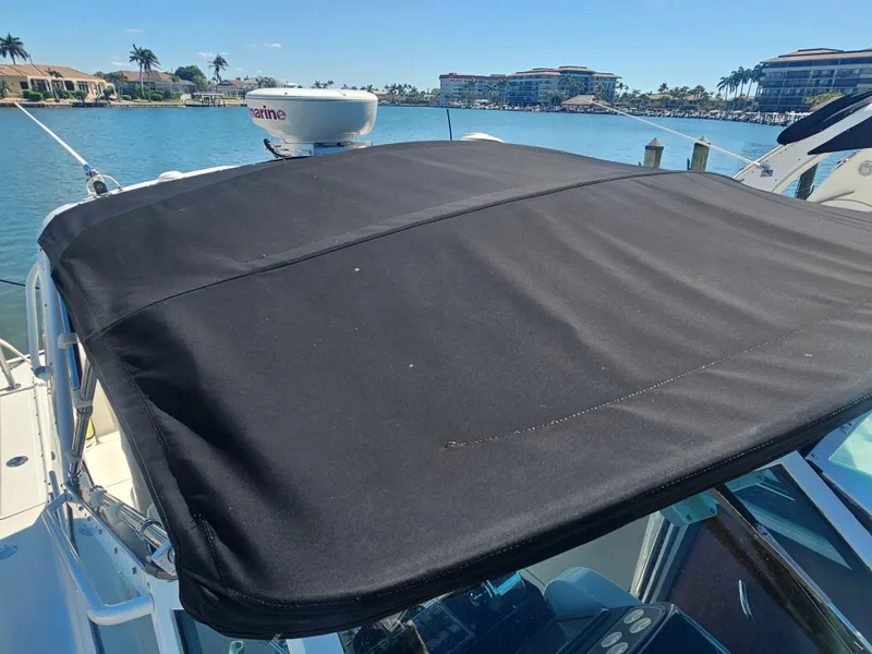 Slide: The Image of 2000 Tiara Yachts 3100 Open with black canvas top, docked in a sunny marina. - 15