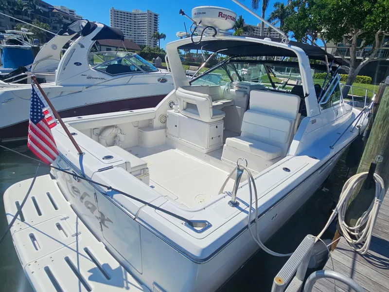 Slide: The Image of 2000 Tiara Yachts 3100 Open docked, featuring spacious deck and American flag. - 8