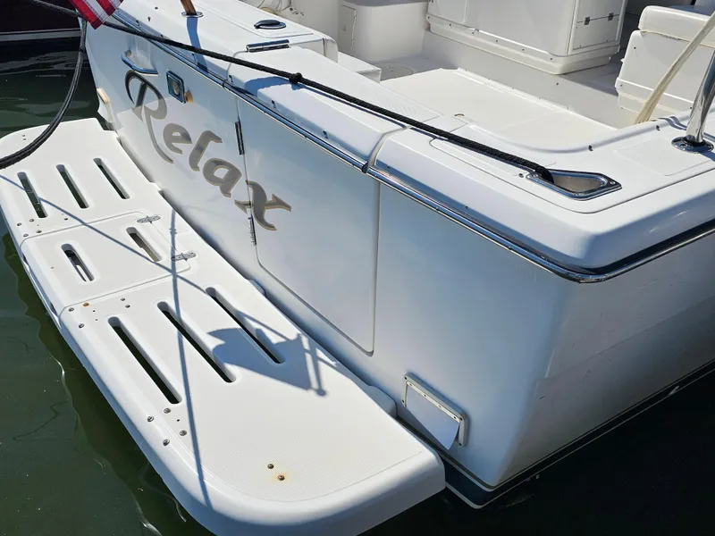 Slide: The Image of 2000 Tiara Yachts 3100 Open boat stern with "Relax" text, docked in water. - 9