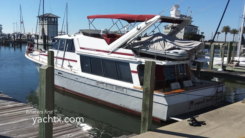 The Image of 1991 Bayliner 4588 Motoryacht docked at marina, featuring red accents and spacious deck. - 1