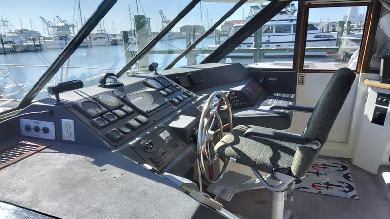 Slide: The Image of 1991 Bayliner 4588 Motoryacht helm with steering wheel, controls, and marina view. - 2