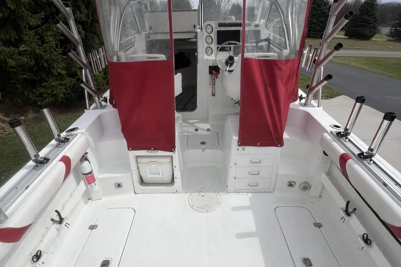 Slide: The Image of 2006 Polar 2300 Walkaround boat interior with red curtains and fishing rod holders. - 4