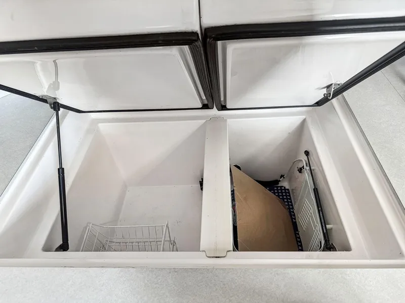 Slide: The Image of Open storage compartment in a 2000 Manta 42 boat, featuring dual lids and wire baskets. - 26