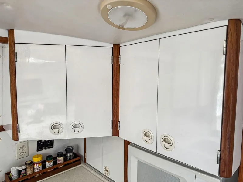 Slide: The Image of White kitchen cabinets with wooden trim in a 2000 Manta 42, featuring spice jars on the counter. - 29