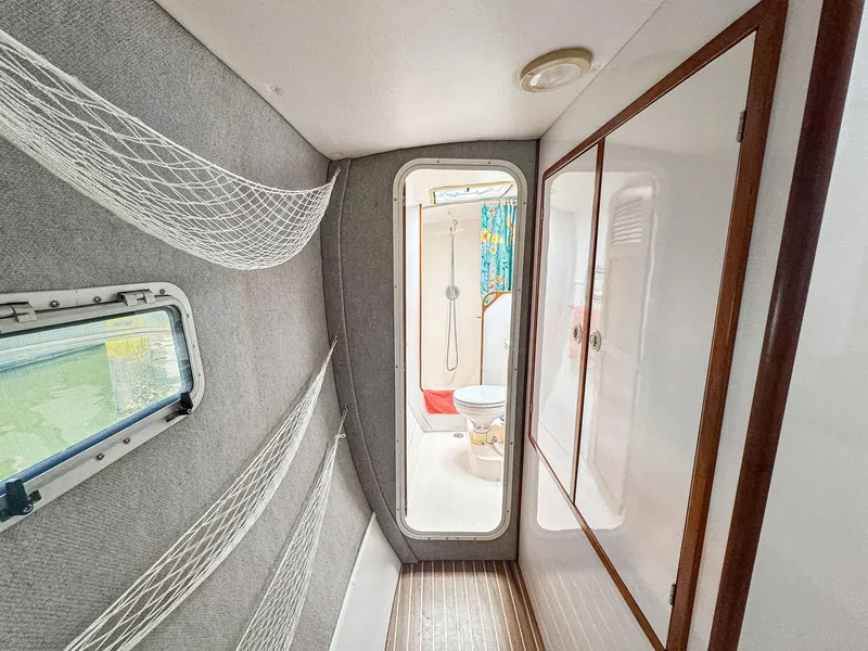 Slide: The Image of Narrow hallway inside 2000 Manta 42 yacht, featuring storage nets and a view into the bathroom. - 33