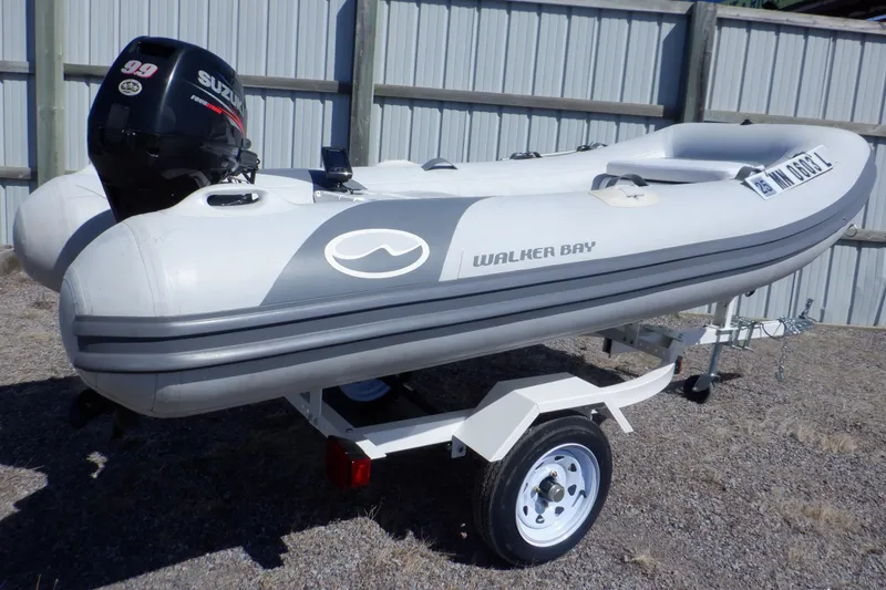 Slide: The Image of 2015 Walker Bay Odyssey 325 ST inflatable boat on trailer with Suzuki outboard motor. - 1