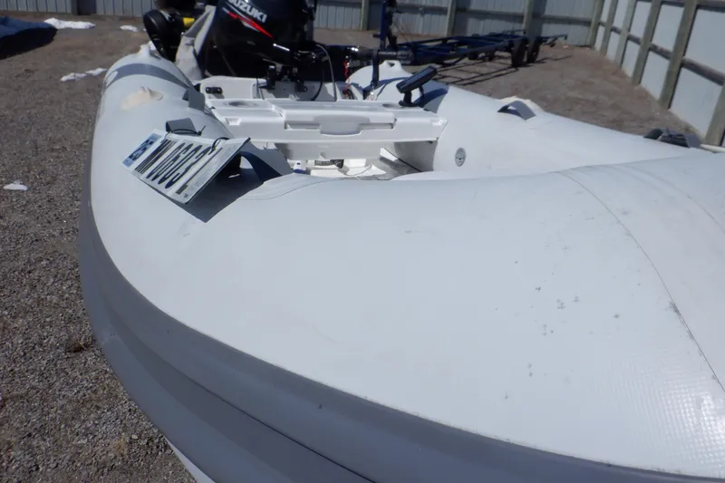 Slide: The Image of Walker Bay Odyssey 325 ST inflatable boat, 2015 model, with outboard motor on gravel surface. - 12