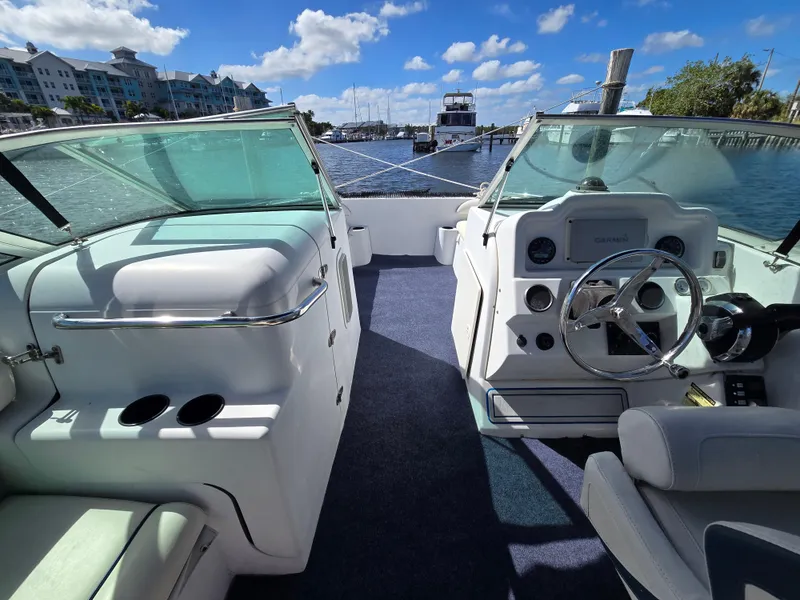 Slide: The Image of 2003 Glacier Bay 2240 SX Renegade boat interior with steering wheel and seating, docked by the water. - 6