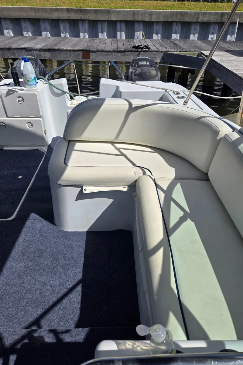 Slide: The Image of 2003 Glacier Bay 2240 SX Renegade boat with cushioned seating and dockside view. - 8