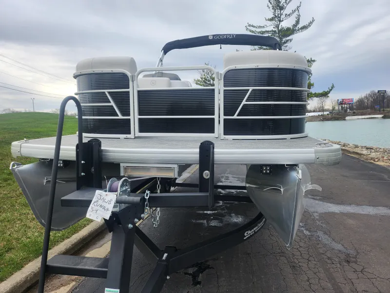 Slide: The Image of 2021 Godfrey Sweetwater 2086 C pontoon boat on trailer, parked near a lake. - 6