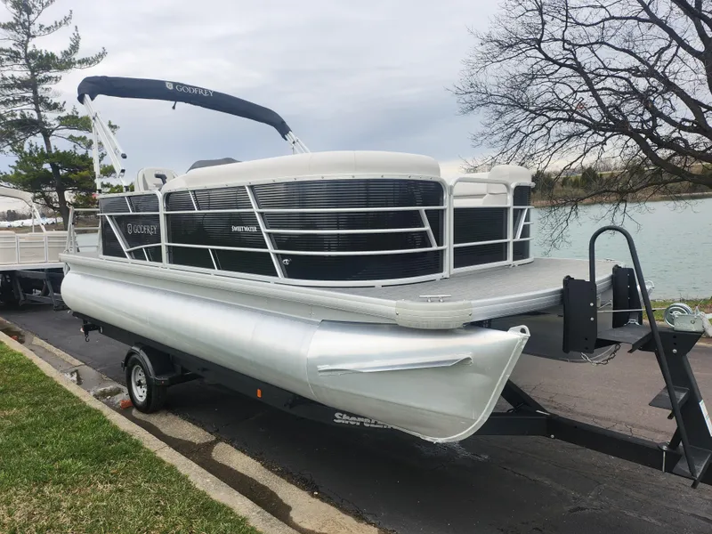 Slide: The Image of 2021 Godfrey Sweetwater 2086 C pontoon boat on trailer by a lake. - 7