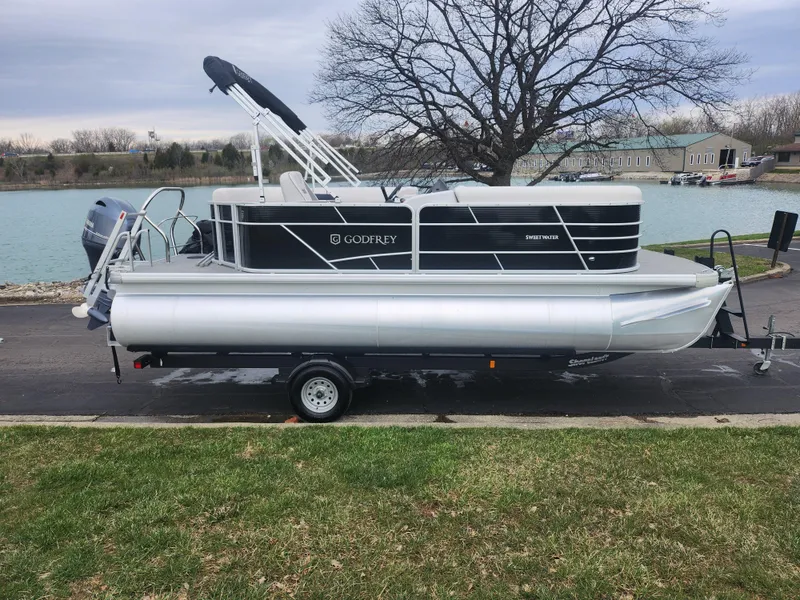 Slide: The Image of 2021 Godfrey Sweetwater 2086 C pontoon boat on trailer by a lake. - 8