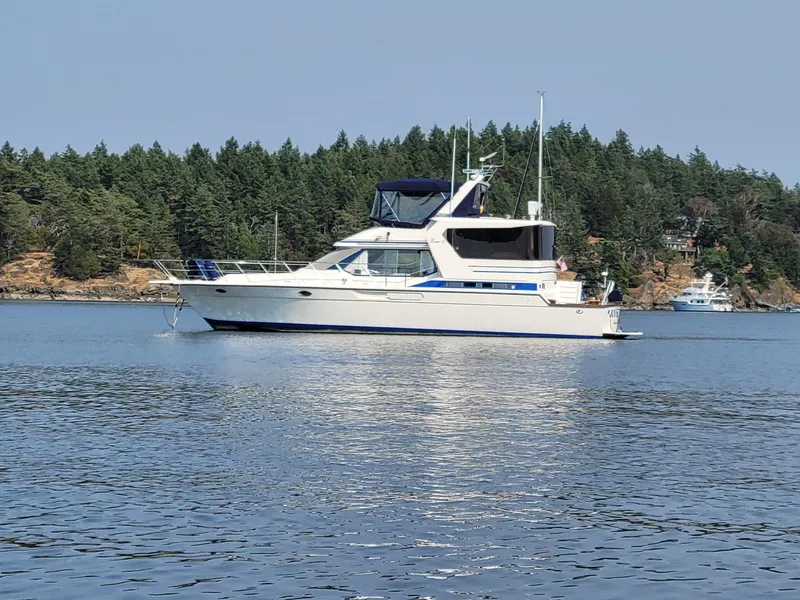 Slide: The Image of 1989 Prima 52 Cockpit Motor Yacht on calm water, forested shoreline in background. - 2