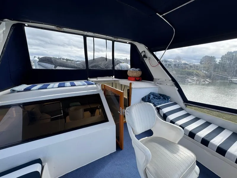 Slide: The Image of 1989 Prima 52 Cockpit Motor Yacht interior with seating, striped cushions, and scenic water view. - 29
