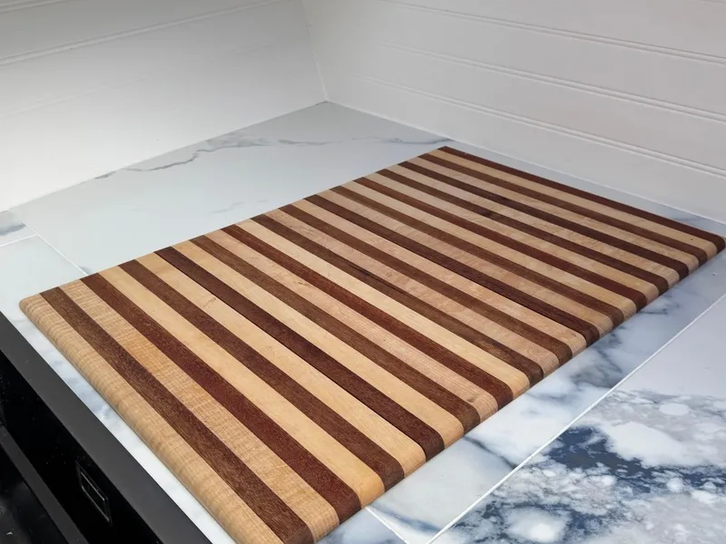 Slide: The Image of Striped wooden cutting board on a marble countertop in a modern kitchen setting. - 49