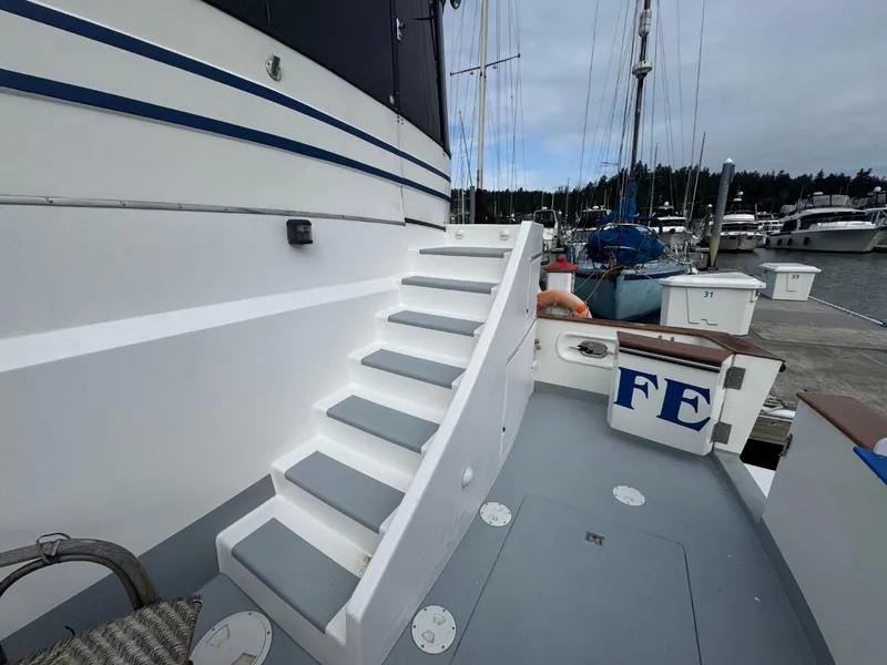 Slide: The Image of Staircase on 1989 Prima 52 Cockpit Motor Yacht at marina, with docked boats in background. - 9