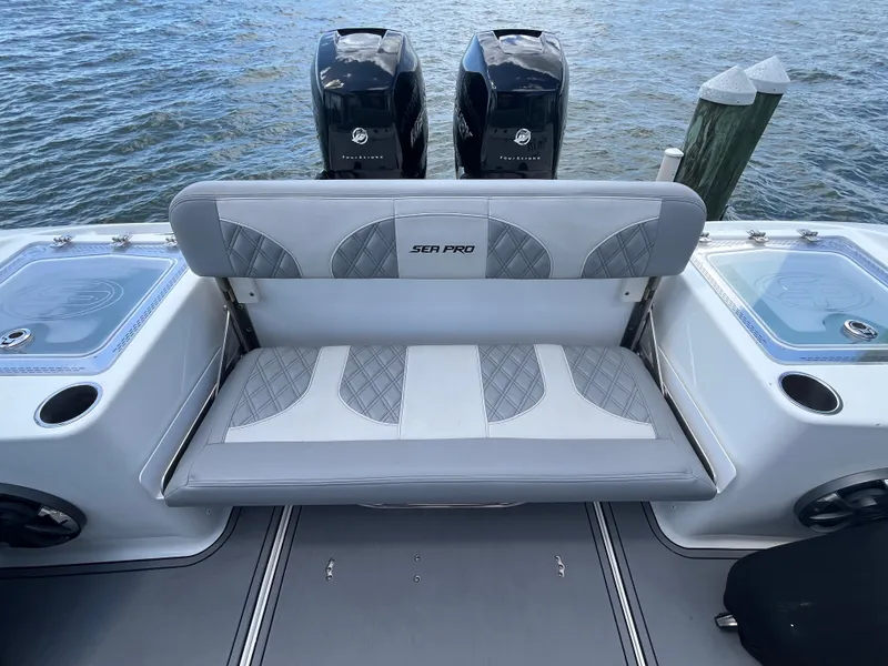 Slide: The Image of 2022 Seapro 320 DLX boat with dual engines and cushioned seating by the water. - 4