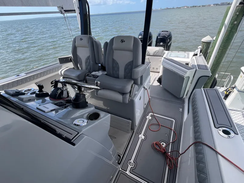 Slide: The Image of 2022 Seapro 320 DLX boat interior with dual seats and control panel, docked by the water. - 6