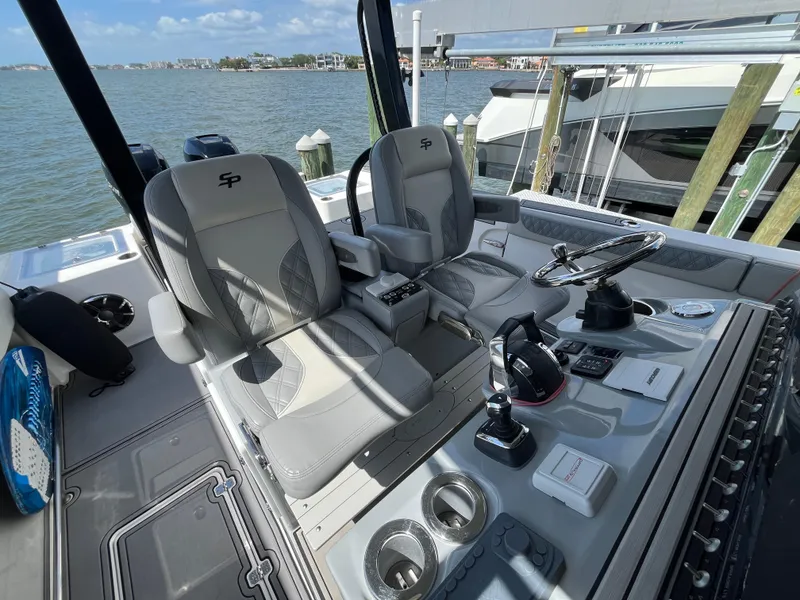 Slide: The Image of 2022 Seapro 320 DLX boat interior with dual seats and control panel, docked by the water. - 7