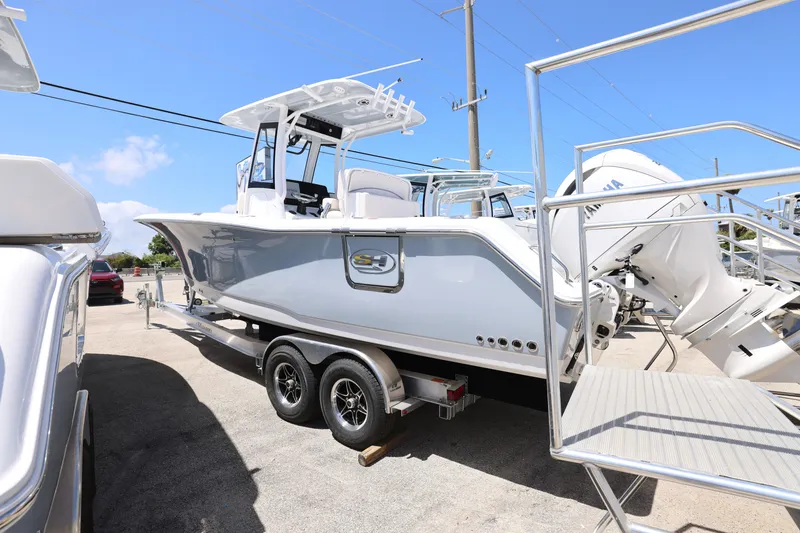 Slide: The Image of 2025 Sea Hunt Gamefish 27 with Coffin Box on trailer, parked outdoors under clear blue sky. - 13