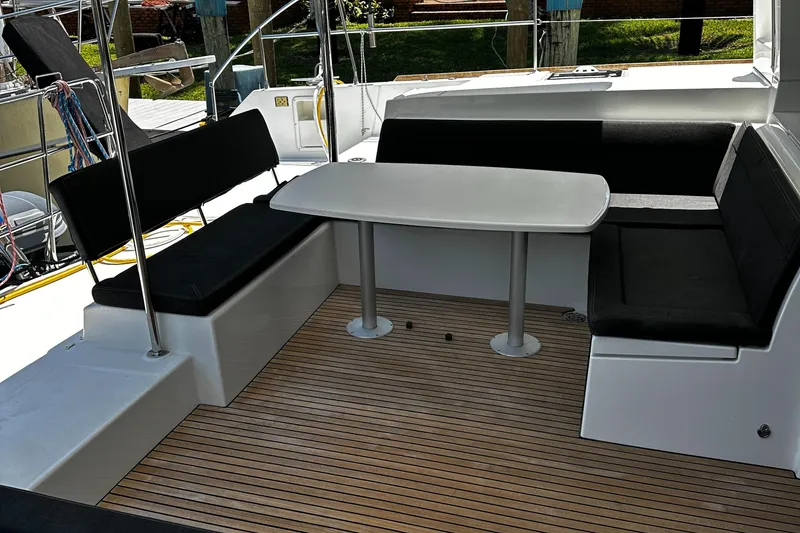 Slide: The Image of Outdoor seating area on 2017 Lagoon 450 F catamaran with wooden deck and cushioned benches. - 14