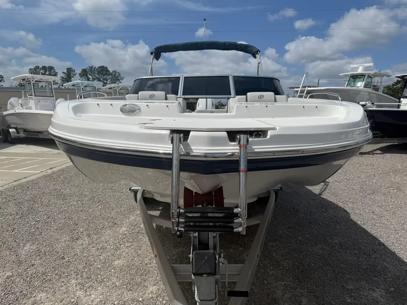 Slide: The Image of 2021 Hurricane SunDeck 217 OB boat on trailer, parked outdoors under a blue sky. - 10