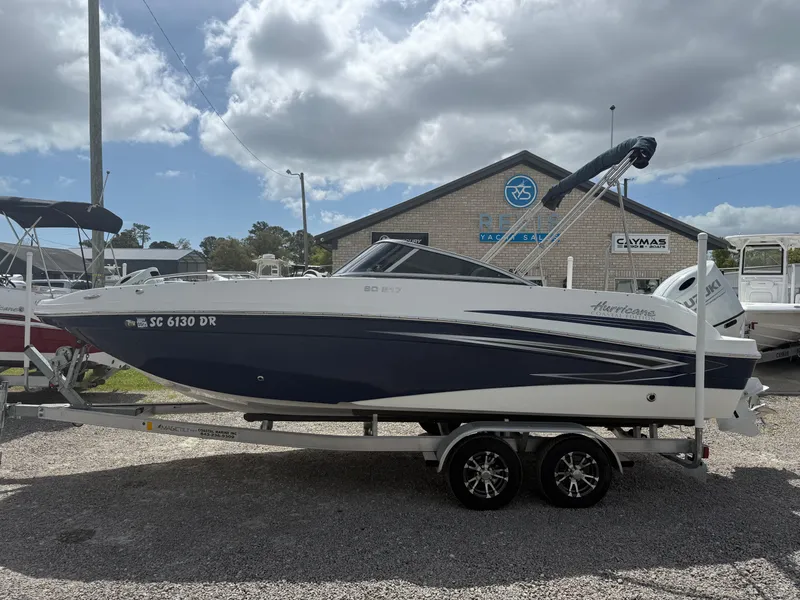 Slide: The Image of 2021 Hurricane SunDeck 217 OB boat on trailer, parked outdoors under cloudy sky. - 2