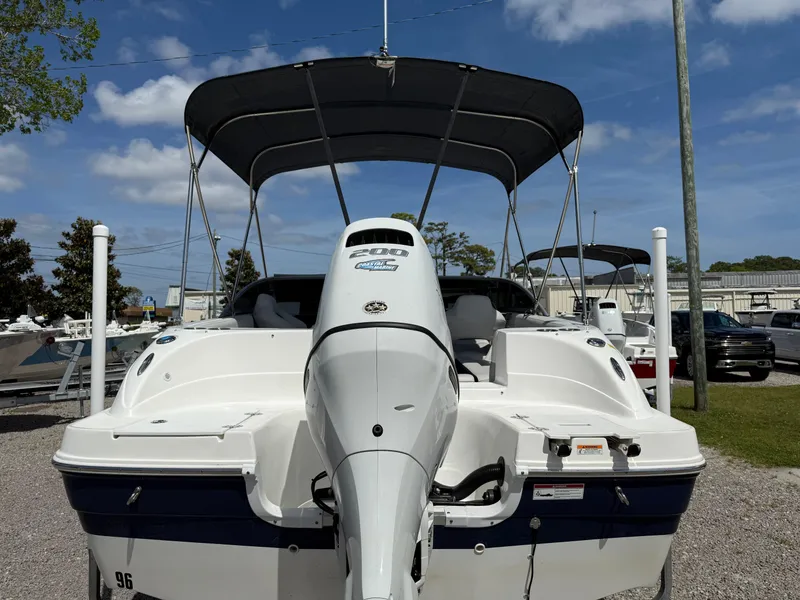Slide: The Image of 2021 Hurricane SunDeck 217 OB boat with canopy, parked outdoors under a clear blue sky. - 29