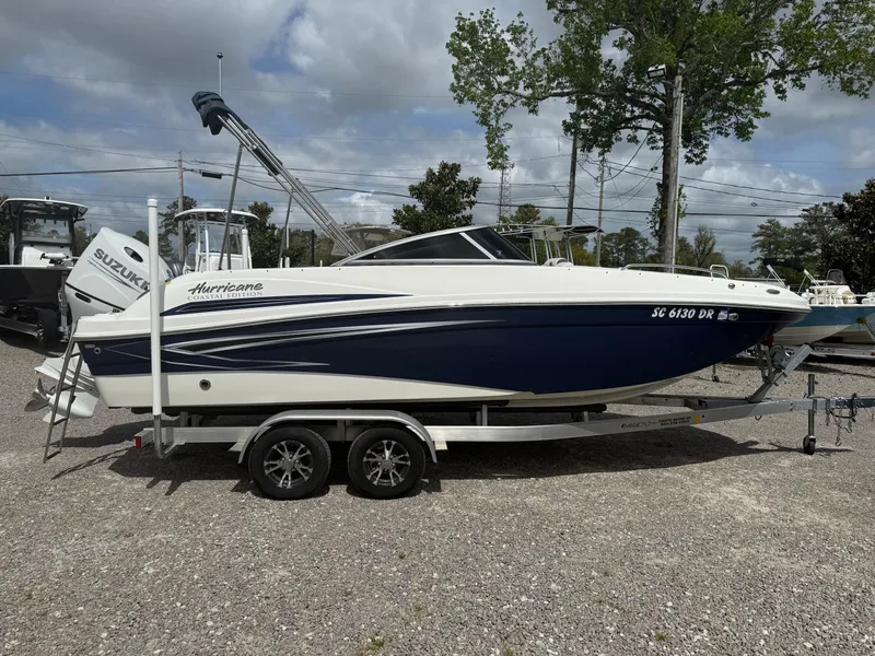 Slide: The Image of 2021 Hurricane SunDeck 217 OB boat on trailer, parked outdoors under cloudy sky. - 7