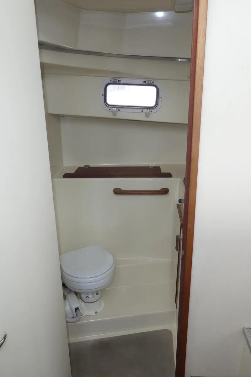 Slide: The Image of 1992 Camano 31 boat bathroom with compact toilet and porthole window. - 22