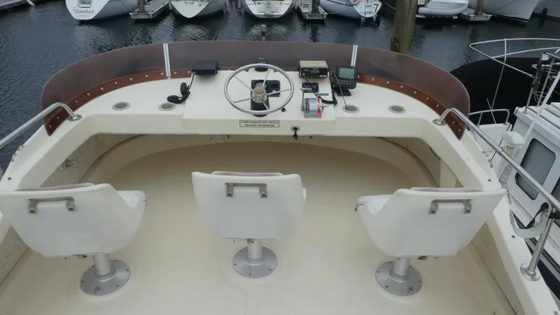 Slide: The Image of 1992 Camano 31 boat helm with three white seats and steering wheel, docked at marina. - 32