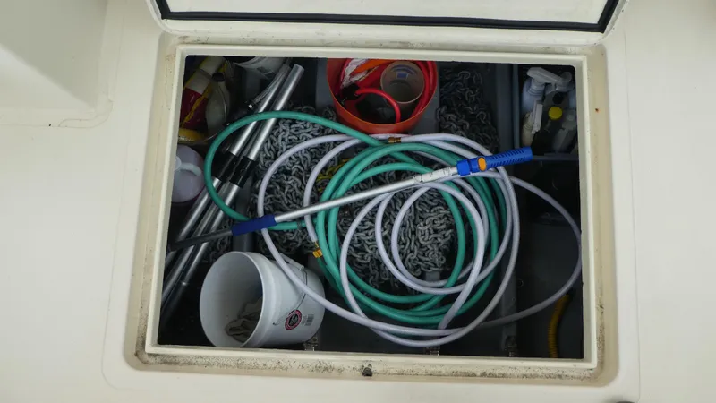 Slide: The Image of Storage compartment on a 1992 Camano 31 boat with hoses and equipment. - 37