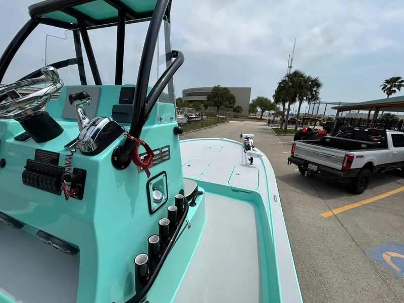 Slide: The Image of 2022 Shallow Sport 25 X3 boat with turquoise console, parked near trucks in a coastal area. - 10