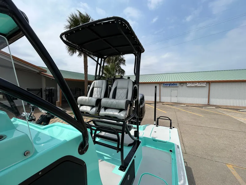 Slide: The Image of 2022 Shallow Sport 25 X3 boat with dual seats and canopy, parked outdoors. - 14