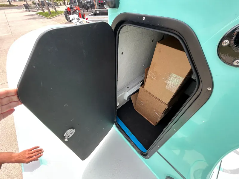 Slide: The Image of 2022 Shallow Sport 25 X3 boat storage compartment with open hatch and cardboard boxes inside. - 15