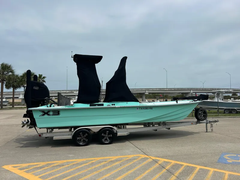 Slide: The Image of 2022 Shallow Sport 25 X3 boat on trailer, mint green hull, parked outdoors. - 17