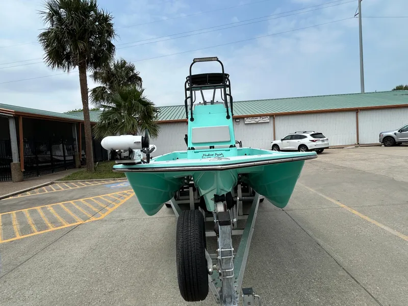 Slide: The Image of 2022 Shallow Sport 25 X3 boat on trailer, parked outdoors near palm trees. - 2
