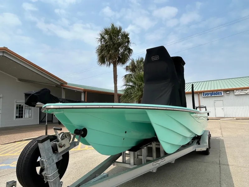 Slide: The Image of 2022 Shallow Sport 25 X3 boat on trailer, parked near palm tree and building. - 21