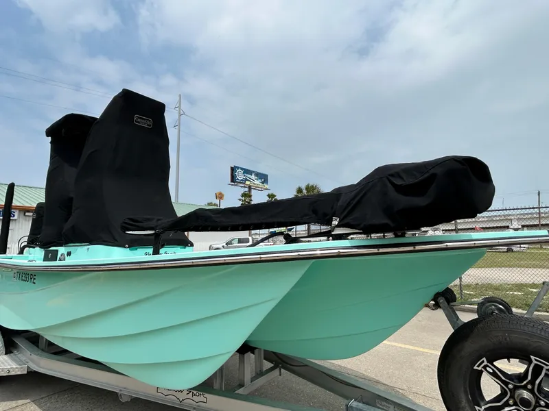 Slide: The Image of 2022 Shallow Sport 25 X3 boat on trailer, turquoise hull, covered seats, outdoor setting. - 22