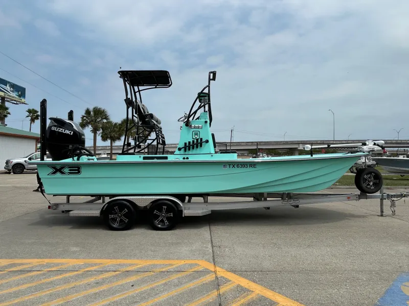 Slide: The Image of 2022 Shallow Sport 25 X3 boat on trailer, mint green, Suzuki engine, outdoor setting. - 4
