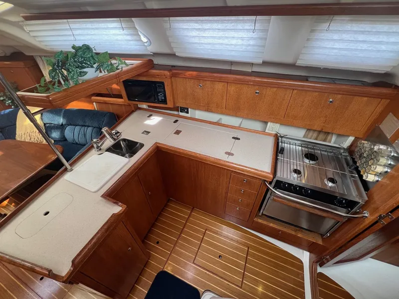 Slide: The Image of 2002 Hunter 386 yacht interior kitchen with wooden cabinetry and modern appliances. - 16