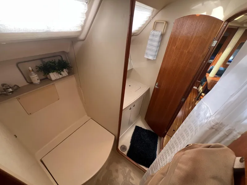 Slide: The Image of Interior of 2002 Hunter 386 sailboat bathroom with shower, sink, and wooden door. - 23