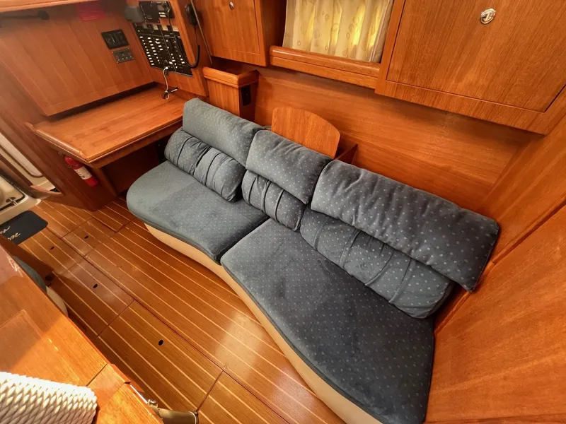 Slide: The Image of Interior of 2002 Hunter 386 sailboat with blue cushioned seating and wooden cabinetry. - 28